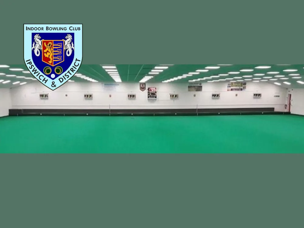 Ipswich & District Indoor Bowling Club logo shown over a photo of a large indoor bowling green with bright lighting, white walls, and scoreboards along the far wall.