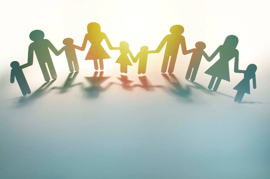 Set of origami people holding hands backlit so that shadows form in front of them
