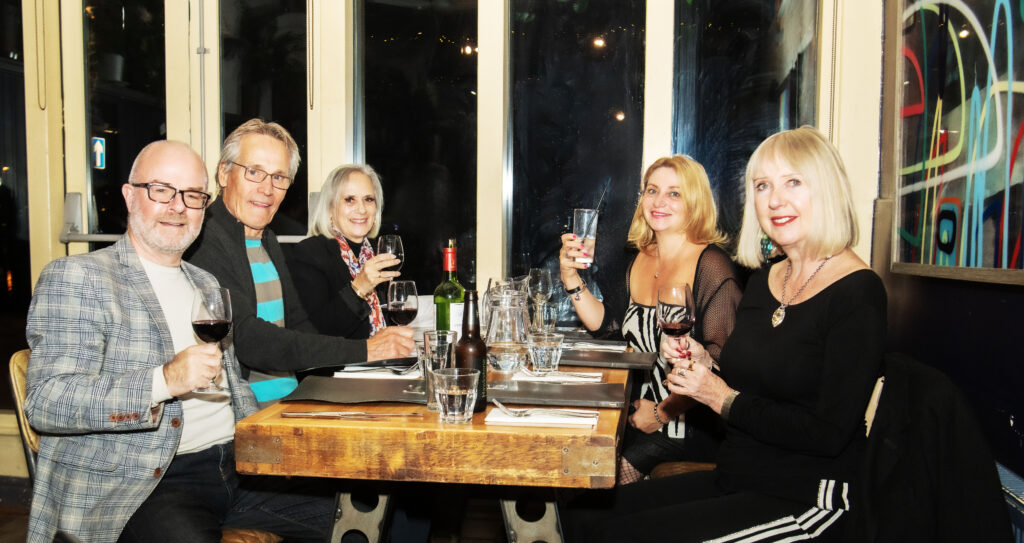 Photograph of 5 people sitting around a table with drinks, mnus and cutlery