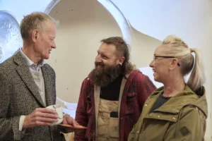 a taller man chatting to two shorter people - one man, one woman